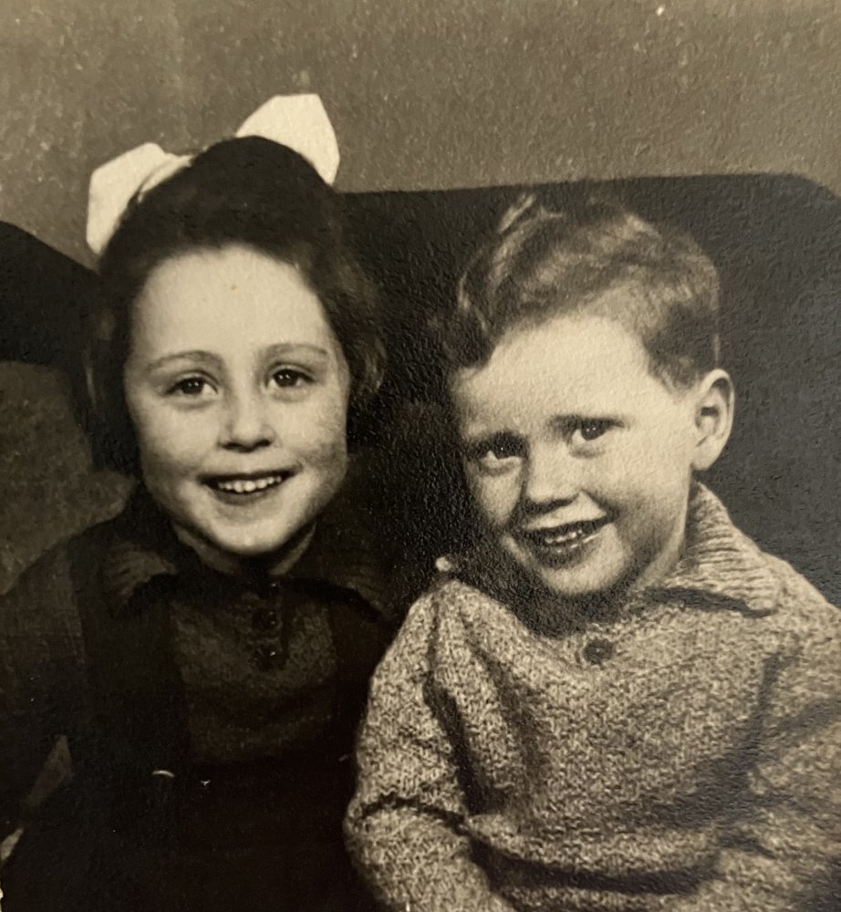 Vivien as a young girl with a white hair bow, sitting beside her little brother