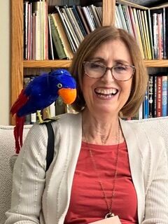 Author Vivien Cooley smiling, with a blue parrot puppet on her shoulder